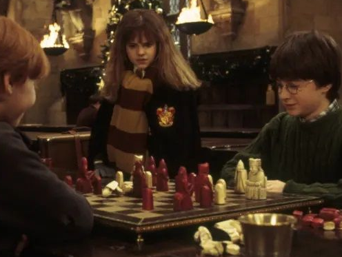 Two schoolchildren play with a red and white Lewis set, while their friend looks on.